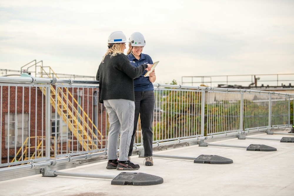Two project managers checking a tablet on a rooftop