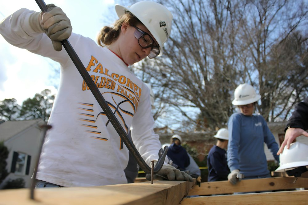 A young woman cutting lumber on a volunteer build