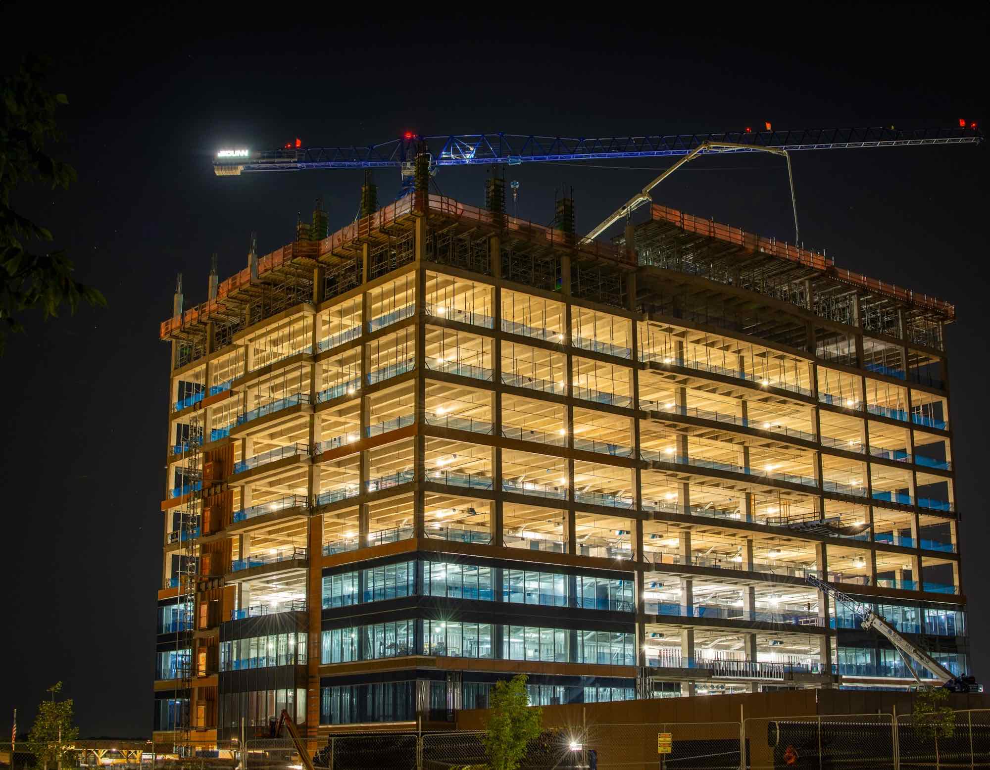 A steel-framed office building under construction, lit at dusk