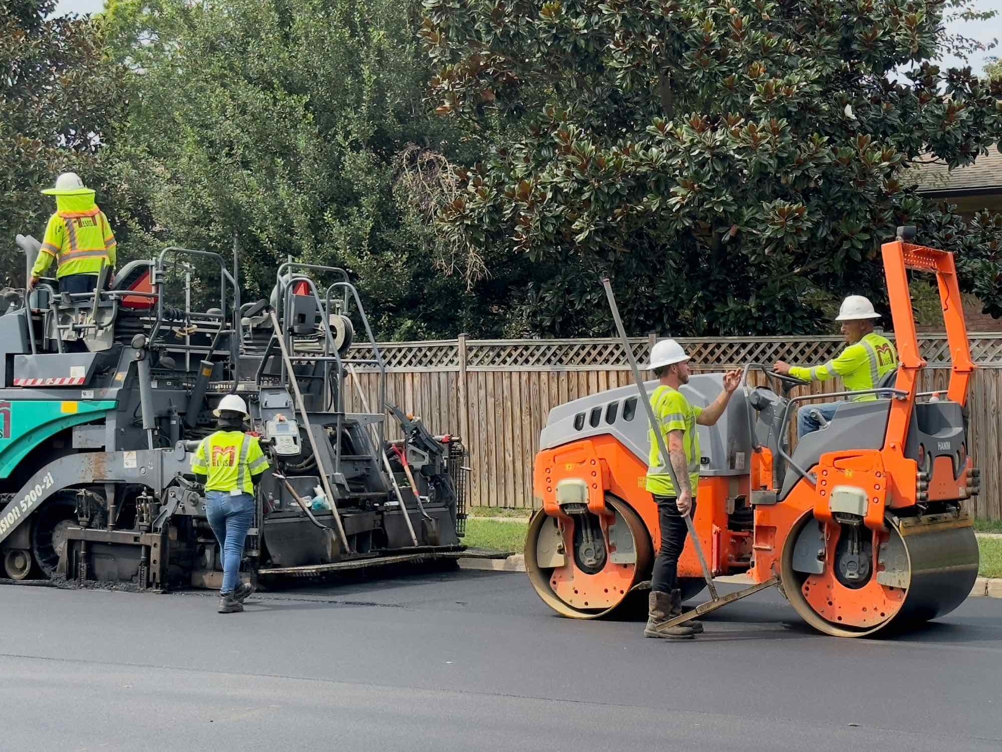 A paving crew laying asphalt on a new residential street