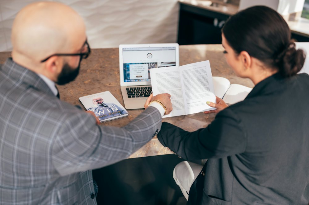 Someone signing a document beside a laptop