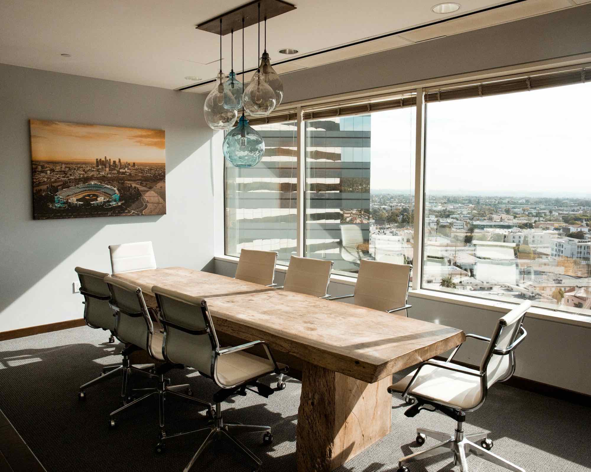 An empty boardroom with a long timber table and a city view