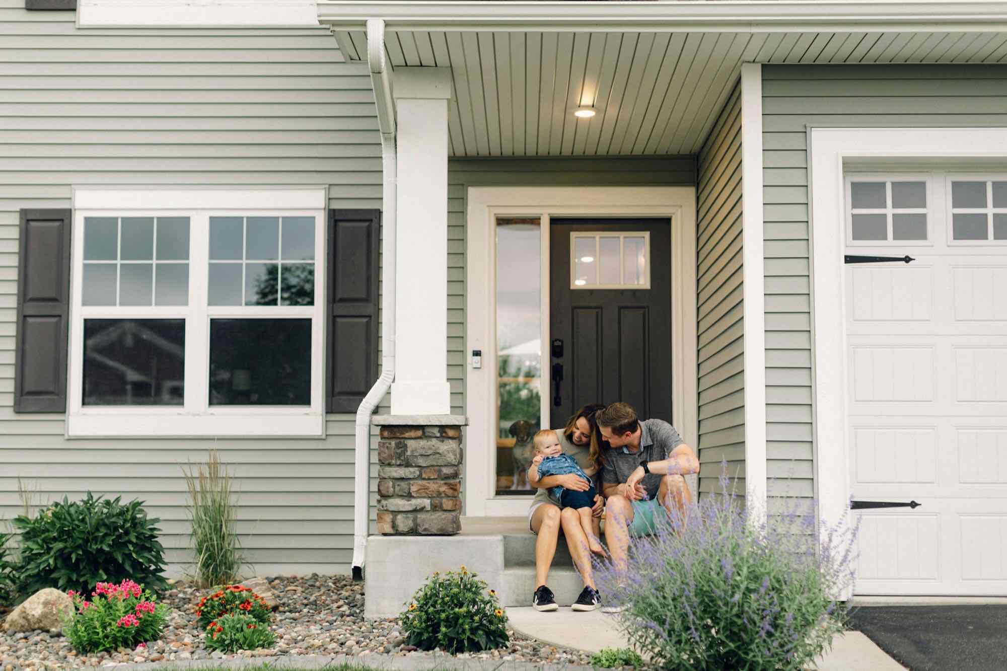 A family sitting on the porch of a newly finished house