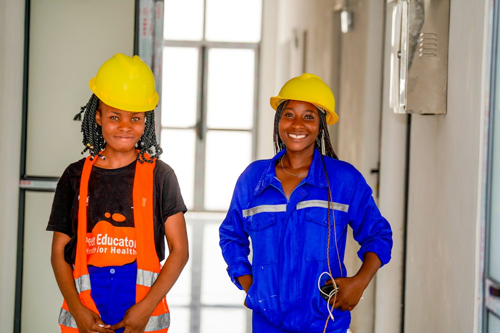Two young tradespeople in yellow hard hats